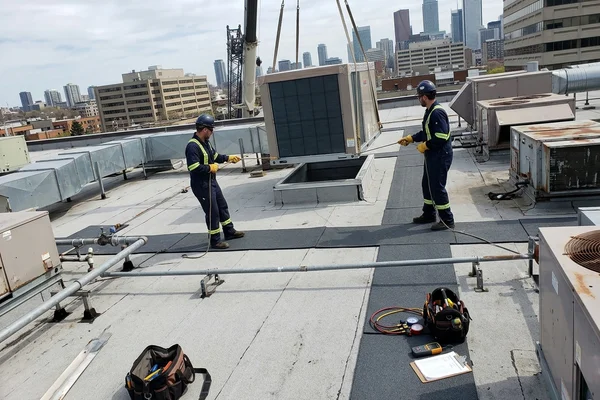 Crane setting a new rooftop unit on a commercial roof