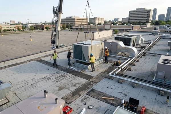 Crane setting a new rooftop unit on a plaza roof