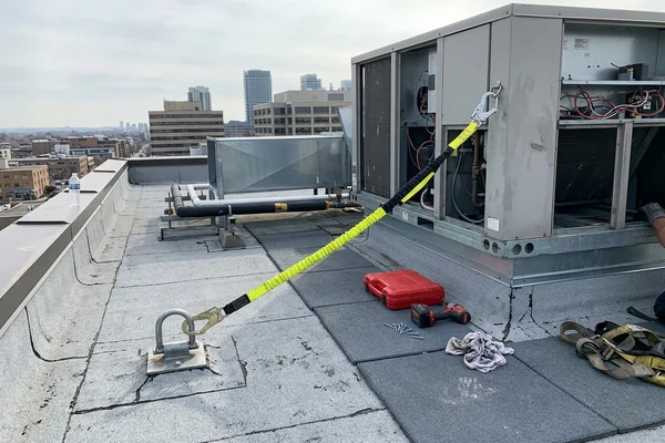 Fall-arrest anchor in use beside a rooftop unit