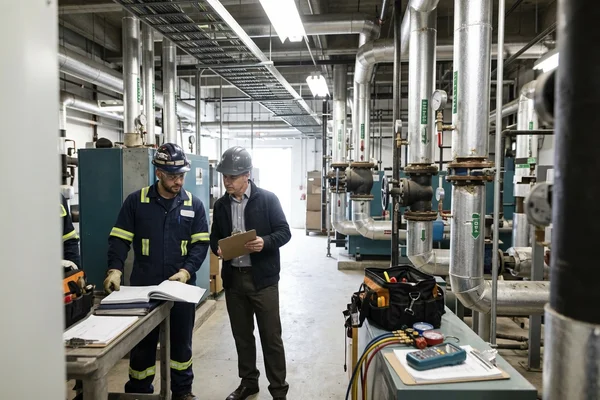 Checking a boiler room log with a building superintendent